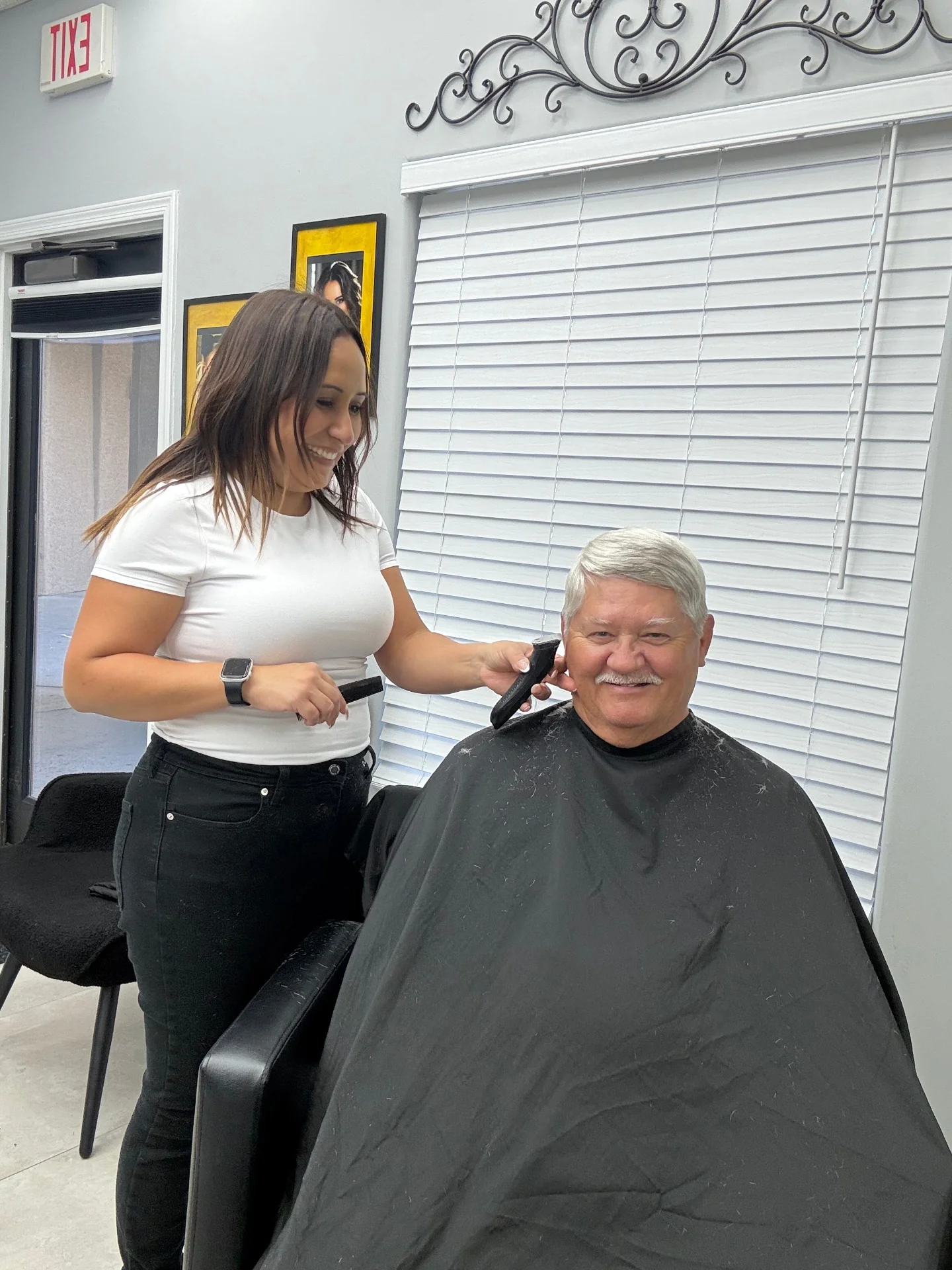 Senior client smiling while receiving clipper detail around the temple from Hair Ambition mobile barber in Goodyear, AZ