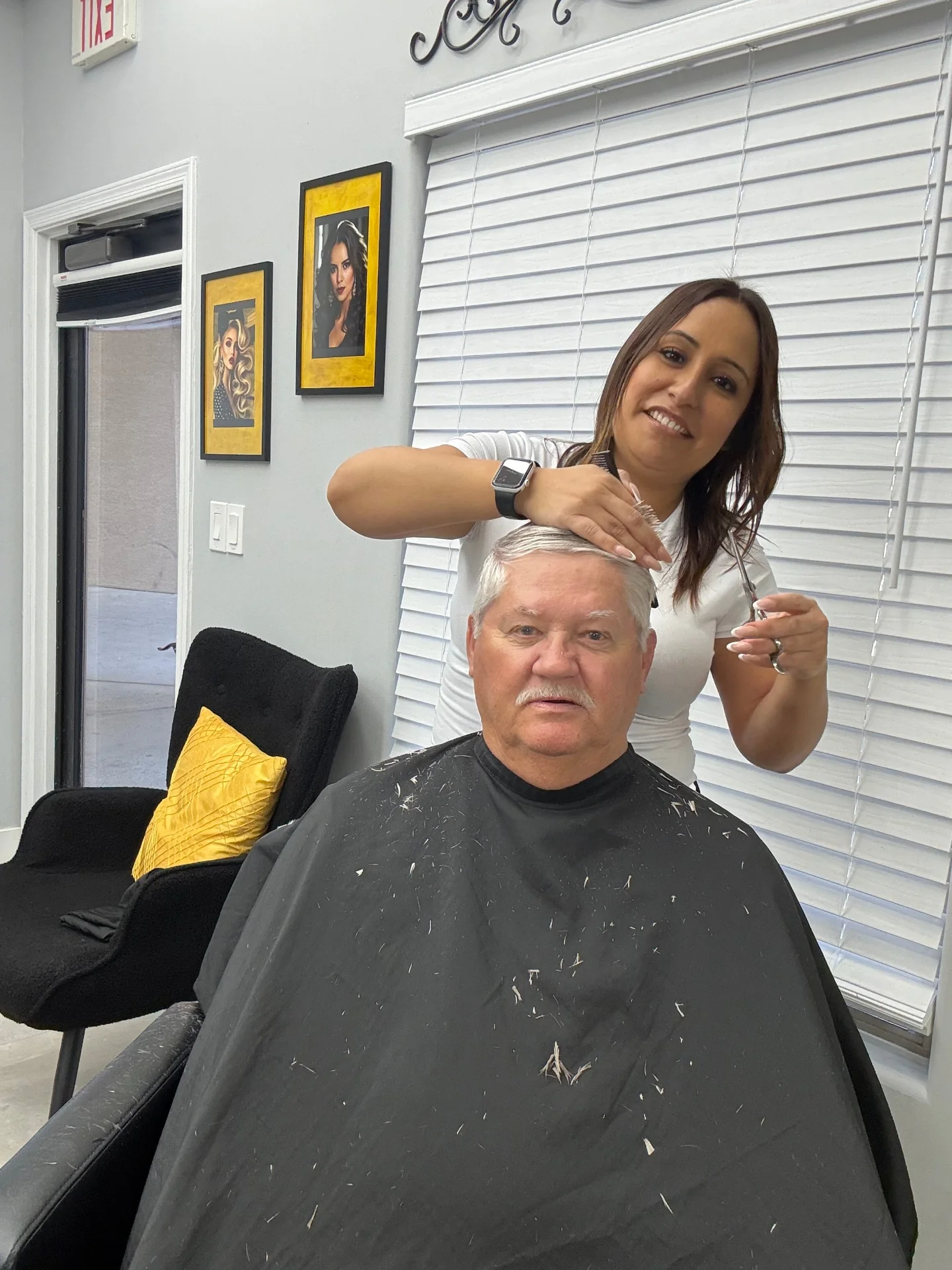 Stylist scissor-cutting the top of a senior client's neatly combed hairstyle at Hair Ambition mobile barber in Goodyear, AZ