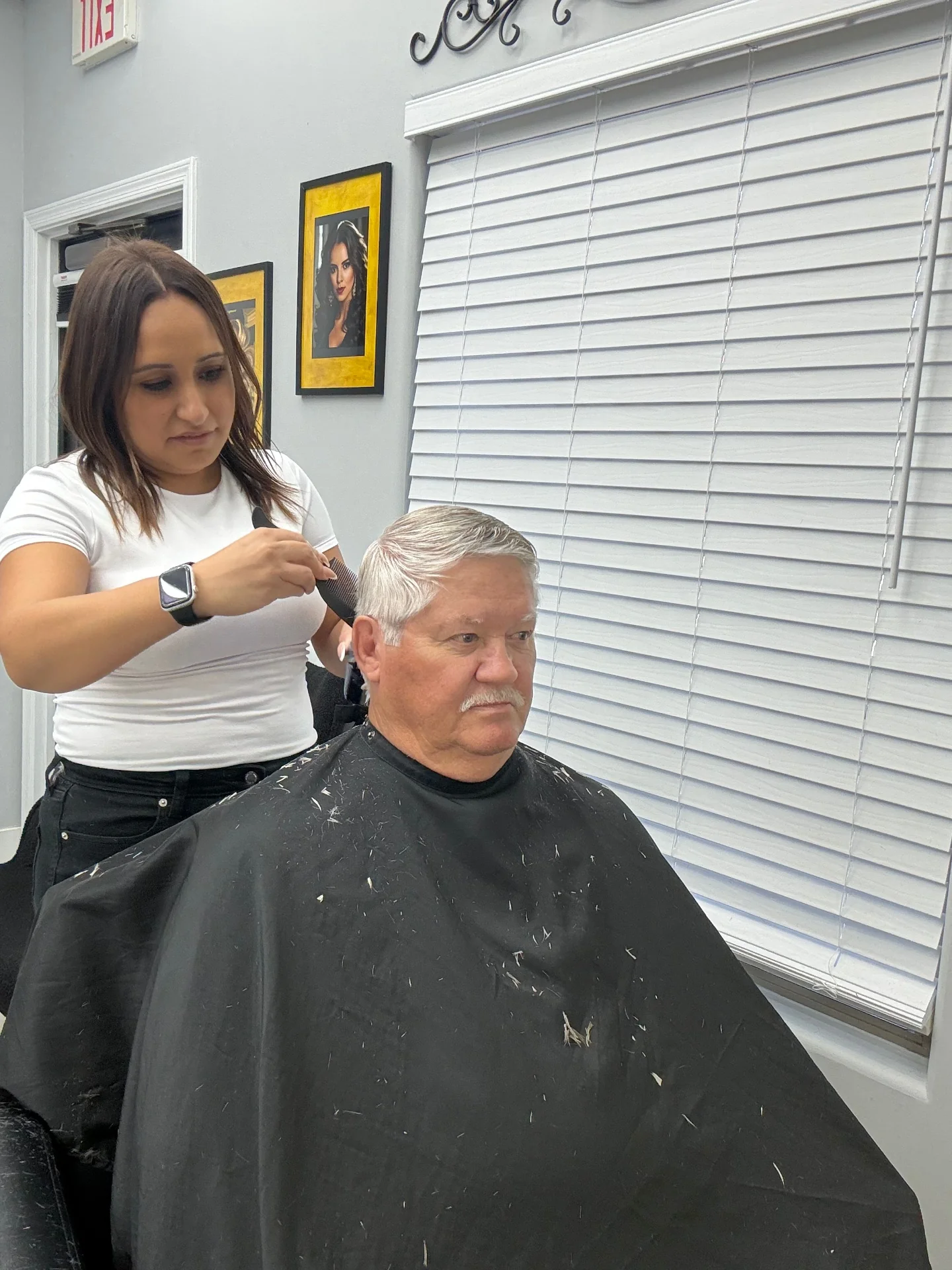 Stylist refining the side of a senior client's haircut with comb and clippers at Hair Ambition mobile barber in Goodyear, AZ